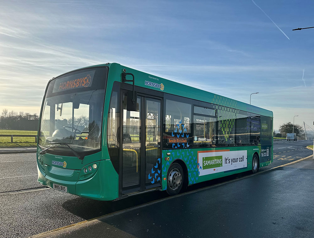 Hornsby Travel Bus parked on a road, with a wrap advertising the Samaritans charity.
